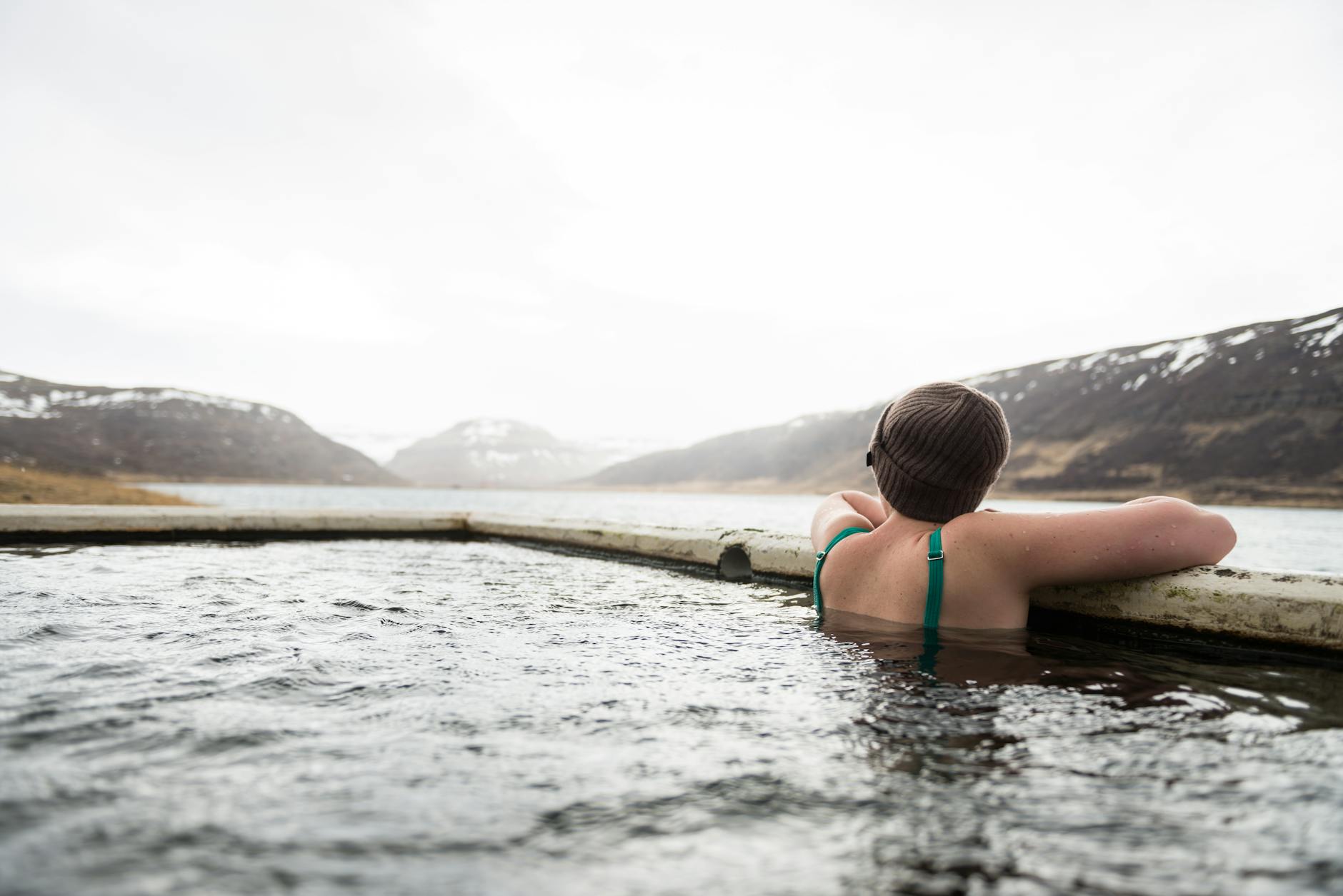 Backpacker relaxing in natural geothermal hot springs surrounded by nature