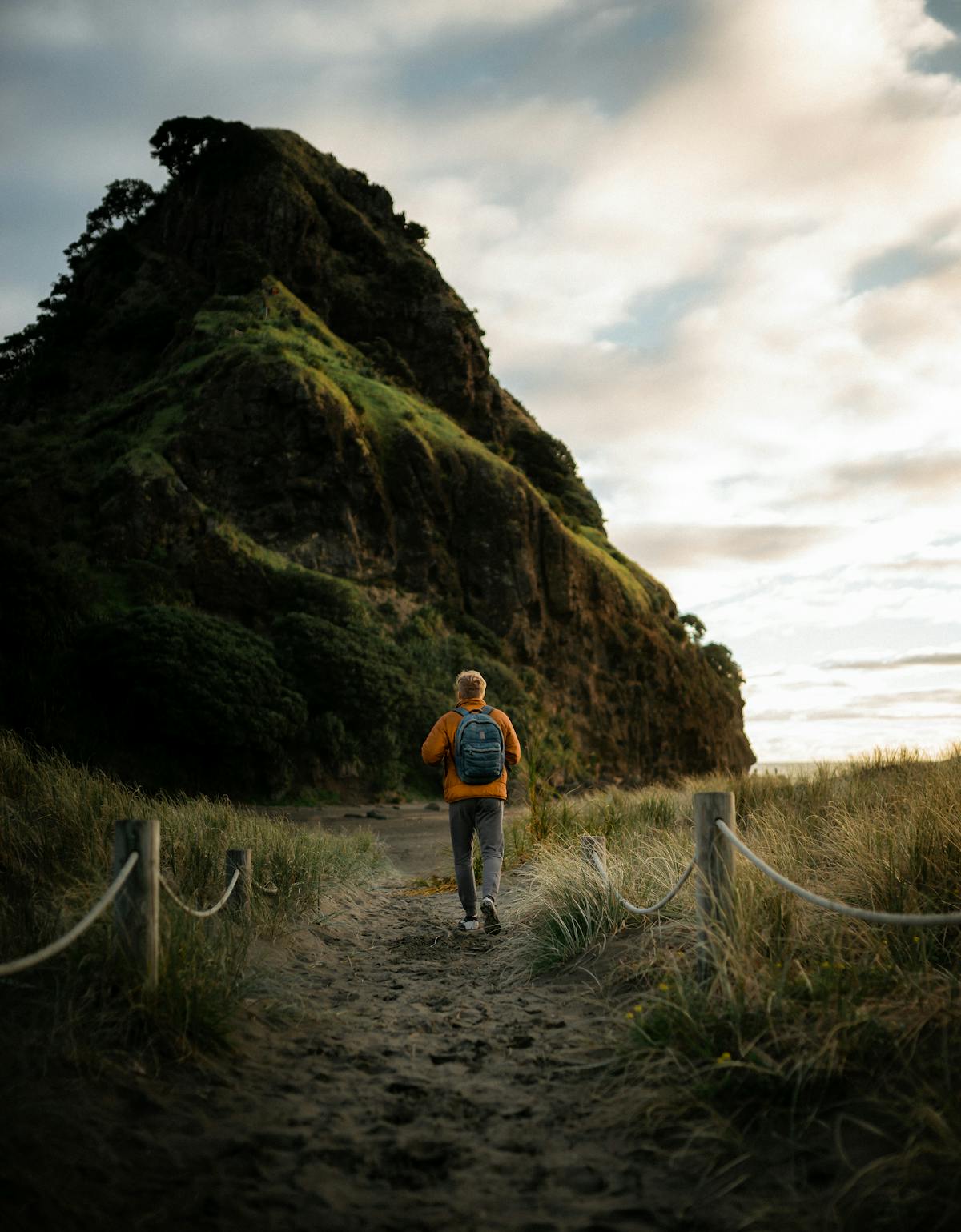 Backpacker walking a scenic trail at sunset in New Zealand with golden light
