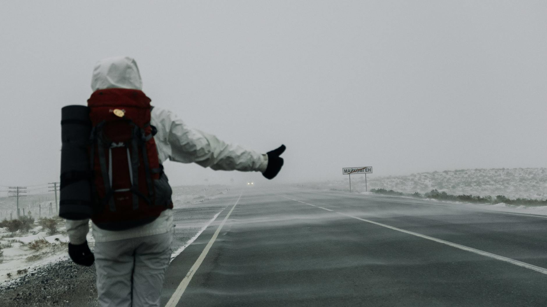 Backpacker with thumb out hitchhiking on a New Zealand country road
