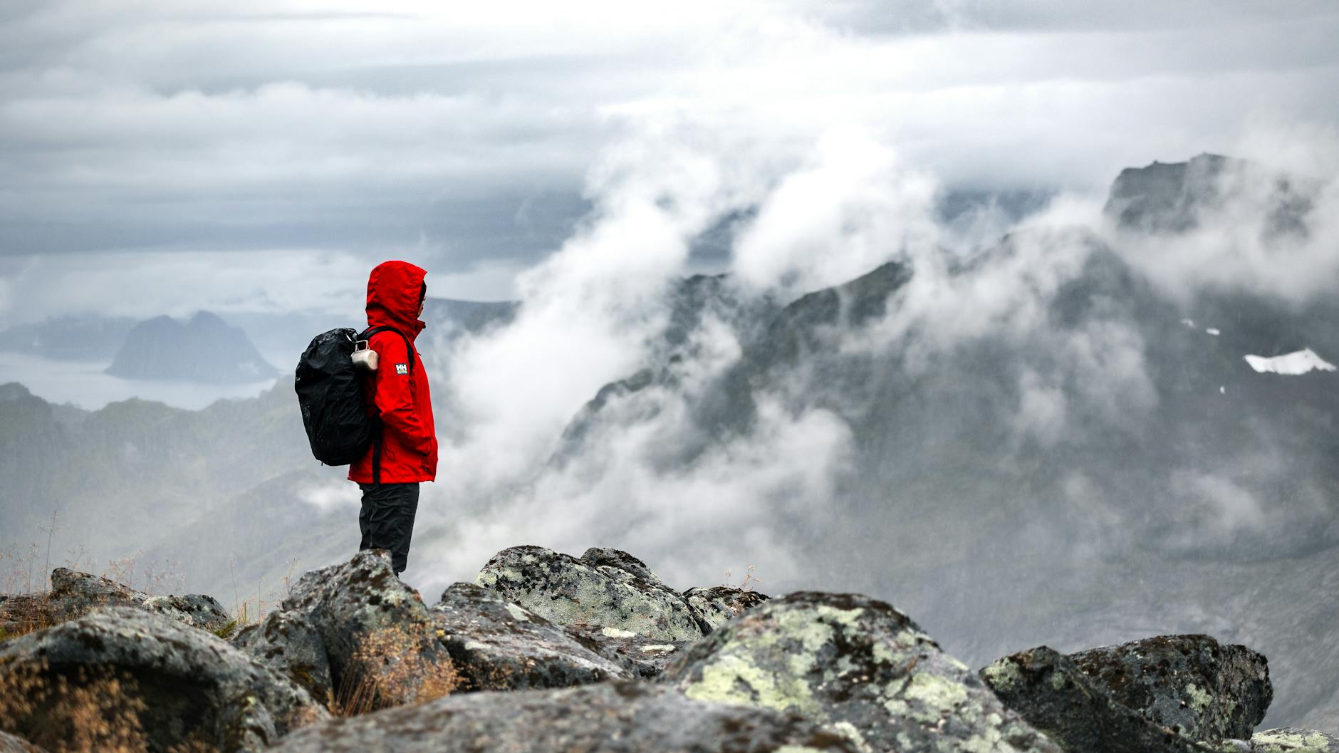 Backpacker wearing layered clothing and rain jacket while hiking in nature