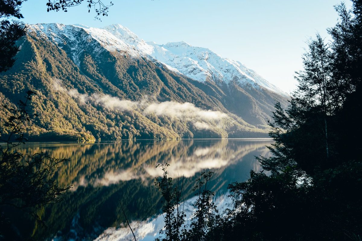 A calm lake below snow-topped mountains