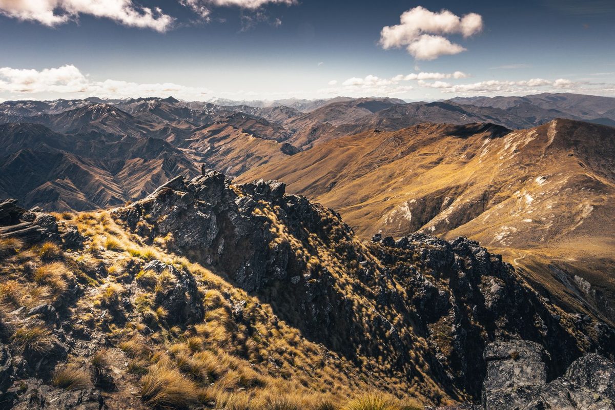 A hiker's-eye view across ridgelines and distant mountain ranges in New Zealand