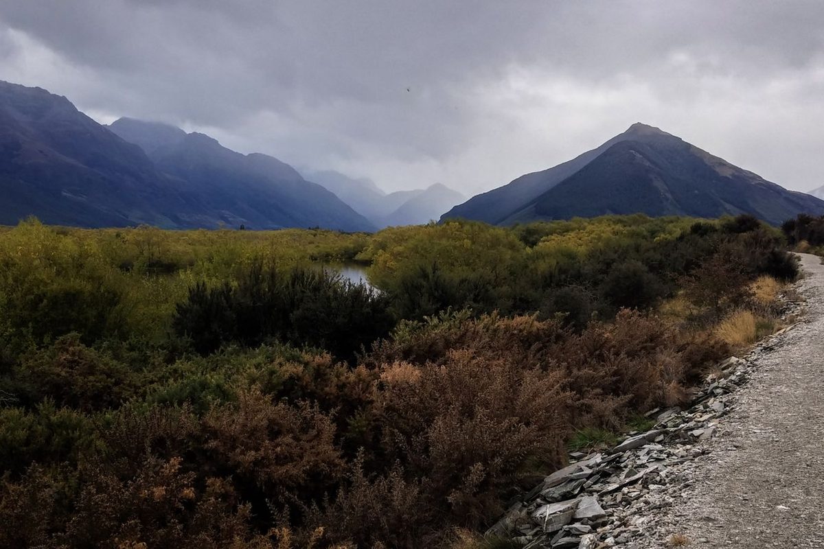 Gravel valley track flanked by scrub, typical alpine approach terrain in New Zealand